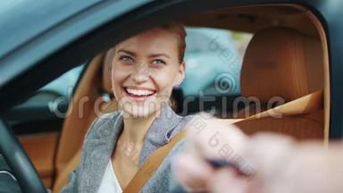 特写微笑的女人坐在<strong>新</strong>车里。 快乐的女人从<strong>新</strong>车里拿钥匙